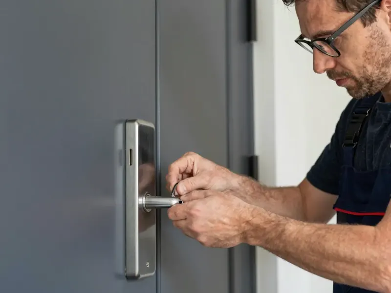 Monteur mit Brille arbeitet am Griff einer Metalltür